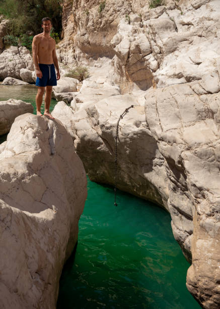 istock Man Jumping into Turquoise Waters at Wadi Bani Khalid 2185612113