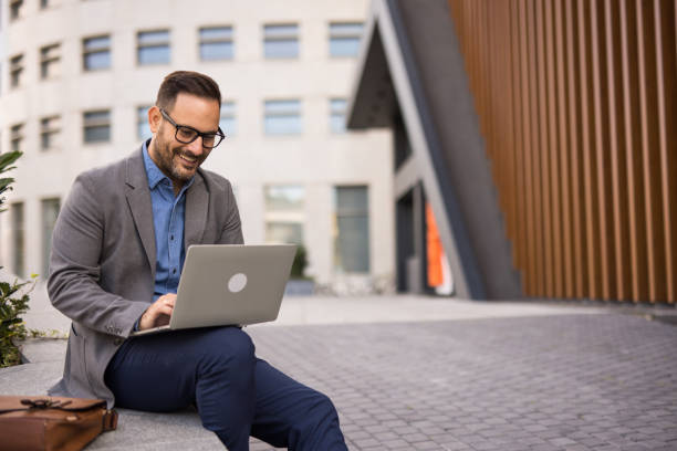 istock Confident businessman working outdoors with laptop in urban setting 2185612327