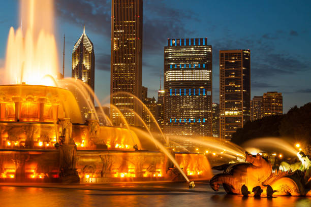 Tourists taking photos at Buckingham Fountain with Chicago skyline in the background in autumn.
