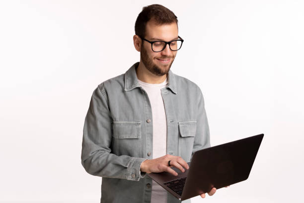 istock young Spanish man holding laptop in front of white backdrop 2185616368