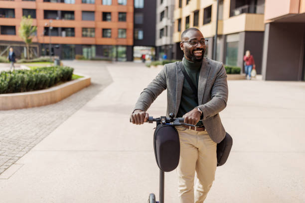 A joyful urban commuter in a gray blazer rides an electric scooter through a vibrant courtyard setting, embodying the essence of modern commuting with energy and style, perfectly set against a backdrop of contemporary architecture.