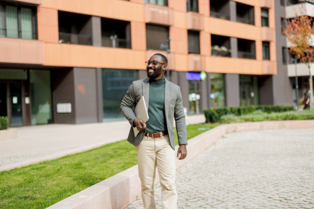 istock Man walking with laptop, confident stride, urban environment. 2185618864