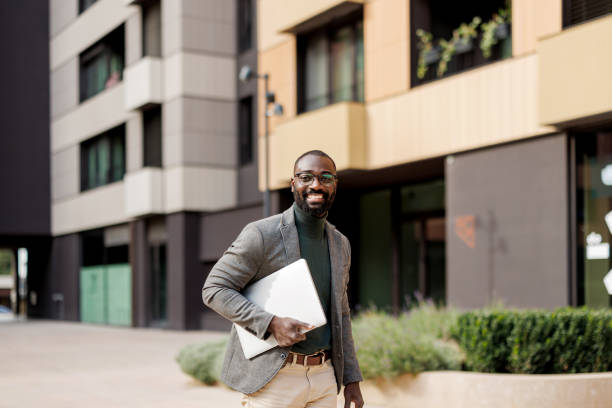 istock Man with laptop stands confidently against modern urban facade 2185618902