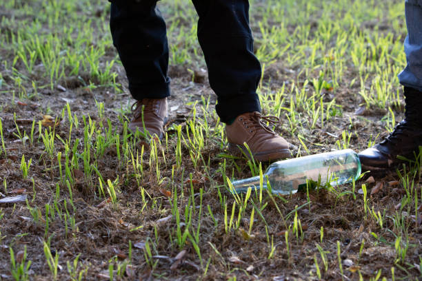 Hikers finding message in a bottle while walking on a grass field