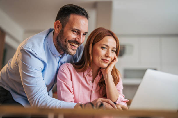 istock A married business couple in the kitchen using a laptop at the table. 2185620947