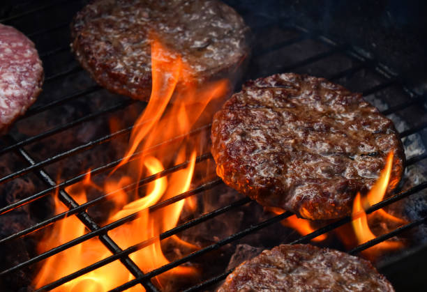 istock Delicious hamburger patties grilling on barbecue fire flames 2185624958
