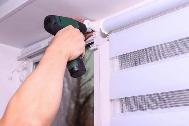 istock Close up of man hands with screwdriver installing roller blinds on window 2185627298