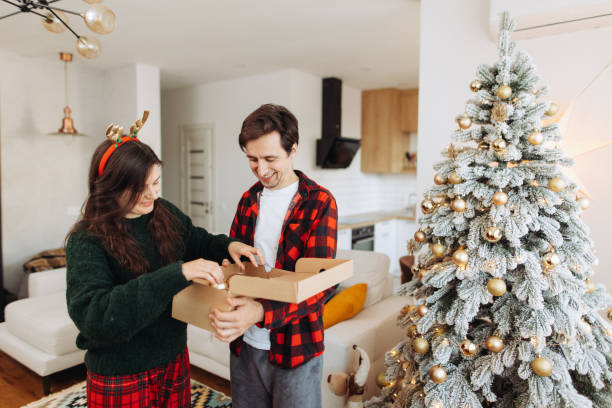 istock Cheerful couple decorating a Christmas tree at home 2185627526