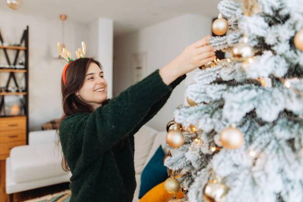 istock Smiling woman decorating a Christmas tree 2185627548