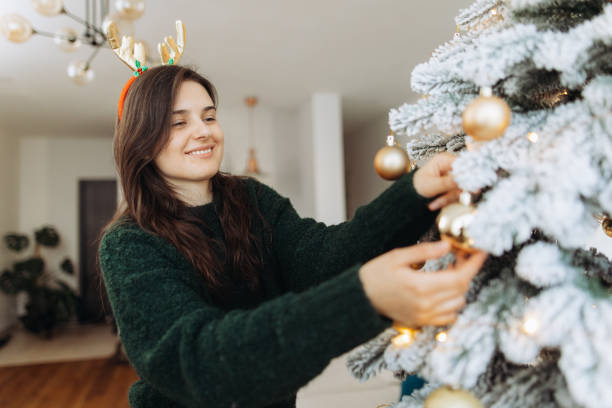 istock Smiling woman hangs a Christmas tree decoration 2185627560