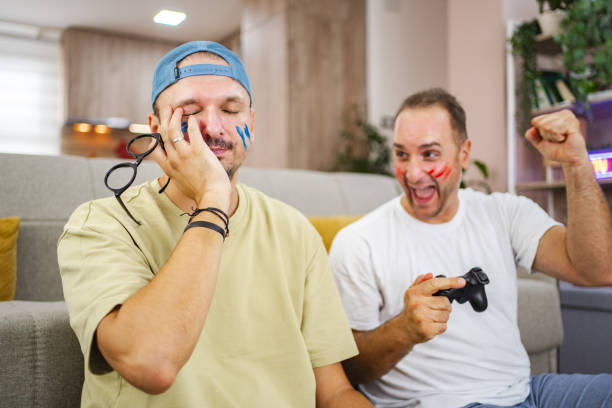 Two friends playing videogames, one is winning and the other is losing