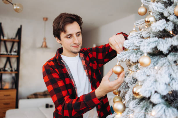istock Smiling man decorating a Christmas tree at home 2185628104