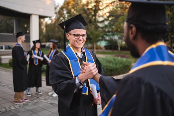 istock Two happy students shaking hands at graduation ceremony 2185628375