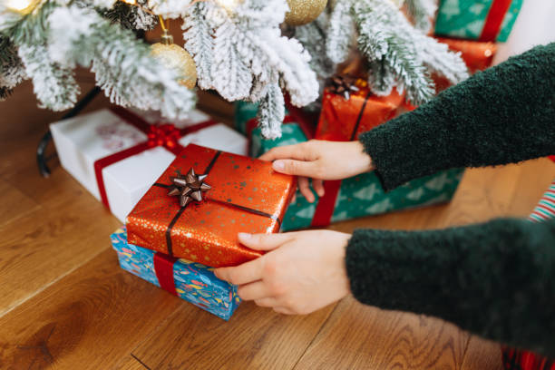 istock Close-up view of a woman's hands taking a gift under the Christmas tree 2185628390