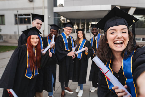 istock Happy graduate students taking a selfie after graduation ceremony 2185628495