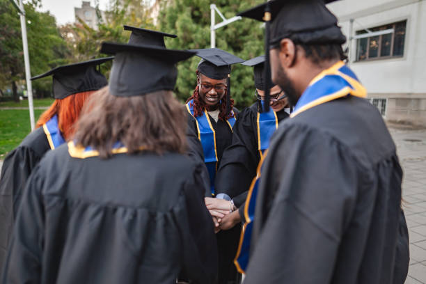 istock Happy graduates joining hands celebrating graduation day 2185628511
