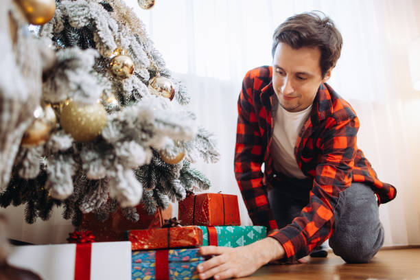 istock The man carefully places a gift under the Christmas tree 2185628636
