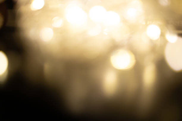 Golden brown Christmas bokeh background. Blurred white garland lights background with glitters and soft reflections for rendering, greeting cards and postcards. Blurry vintage gold abstraction.