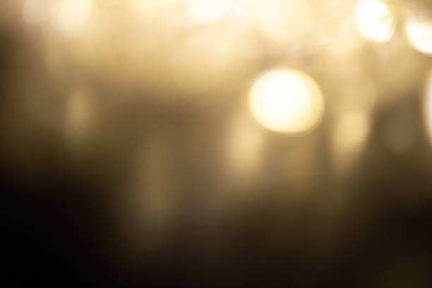 Golden brown Christmas bokeh background. Blurred white garland lights background with glitters and soft reflections for rendering, greeting cards and postcards. Blurry vintage gold abstraction.