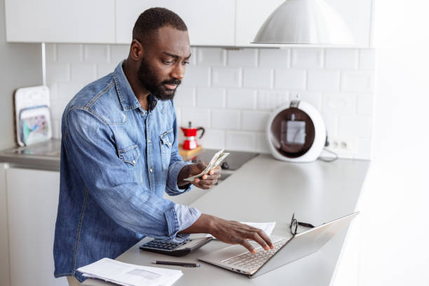 istock Young man manages bills and expenses, using a laptop at home 2185632403