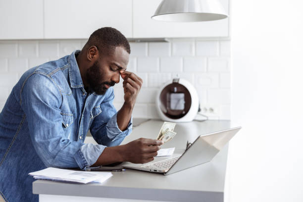istock Young man manages bills and expenses, using a laptop at home 2185632405