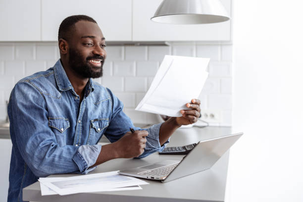 istock Smiling man working from home on laptop in the kitchen 2185632408