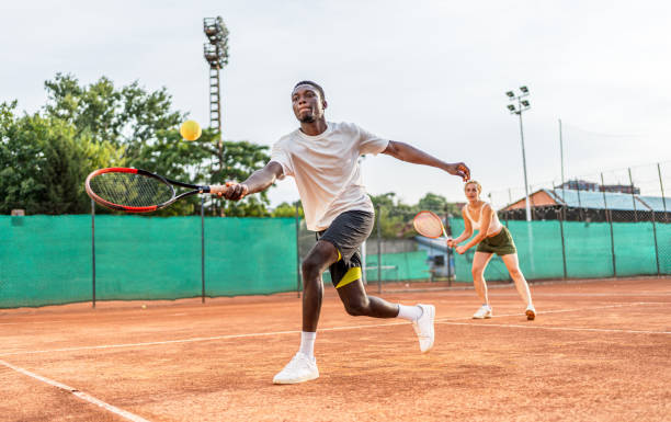Young man playing tennis with his teammate on the clay court