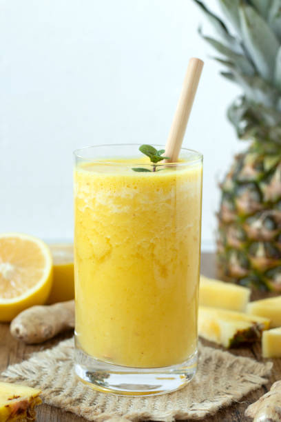 istock Pineapple ginger lemon smoothie in glass with bamboo straw on wooden table with white background 2185643407