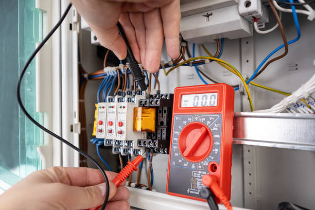 istock Hands holding probes connected to a multimeter for testing an electrical circuit in a control panel 2185643665