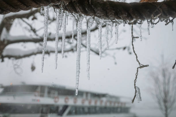 Close-up of icicles hanging from a rope along the Bosphorus on a snowy day in Istanbul. The blurred background of the wintery waterfront adds depth to the serene and chilly atmosphere, highlighting the beauty of nature's frozen details in an urban setting.\