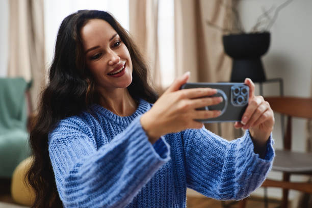 istock A woman smiles while taking a selfie in a cozy indoor setting 2185645868