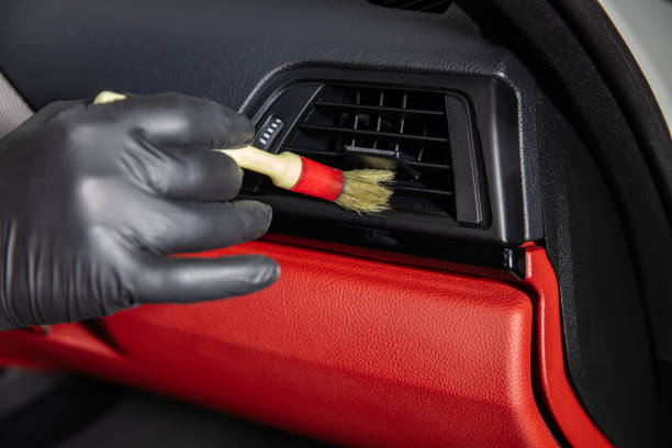 istock Brush cleaning off dust from the car interior details, control panel of the windows. A man cleaning car with cloth and brush. Car detailing. Brush and cleaning solution to clean the interior. 2185646345
