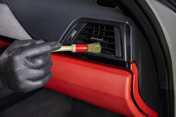 istock Brush cleaning off dust from the car interior details, control panel of the windows. A man cleaning car with cloth and brush. Car detailing. Brush and cleaning solution to clean the interior. 2185646972