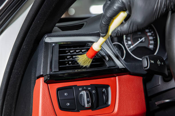 istock Brush cleaning off dust from the car interior details, control panel of the windows. A man cleaning car with cloth and brush. Car detailing. Brush and cleaning solution to clean the interior. 2185647000