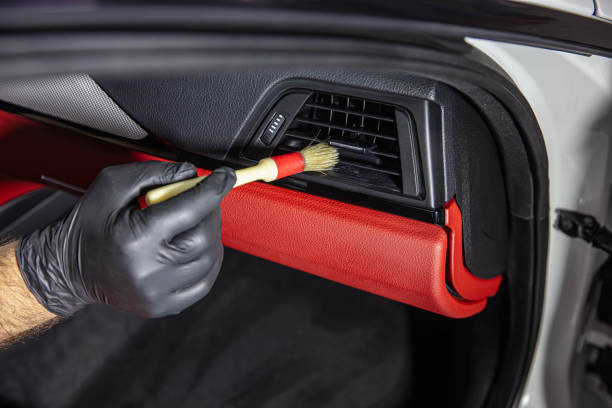 istock Brush cleaning off dust from the car interior details, control panel of the windows. A man cleaning car with cloth and brush. Car detailing. Brush and cleaning solution to clean the interior. 2185647019