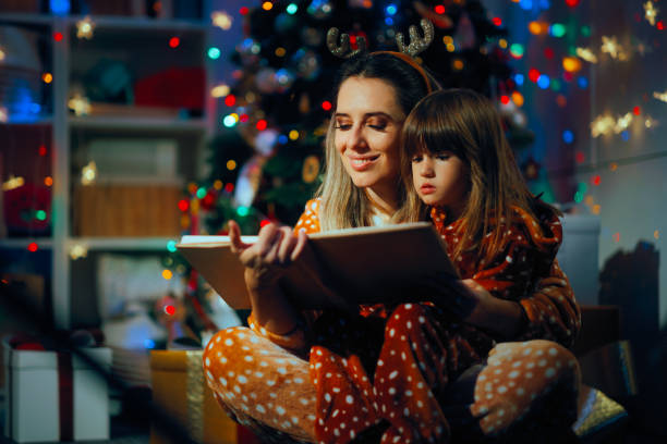 istock Mother and Daughter Reading a Story under the Christmas Tree 2185651182
