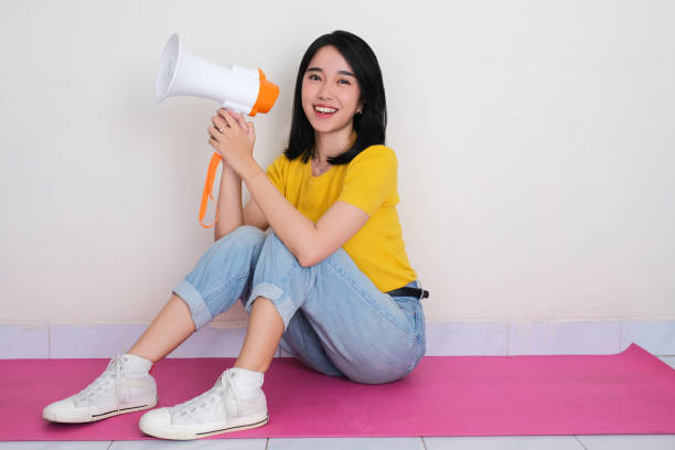 istock A woman sitting on the floor holding megaphone with excited expression 2185652274
