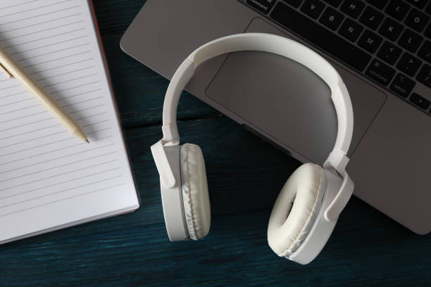 istock Headphones with notebook and laptop on a blue background 2185660687