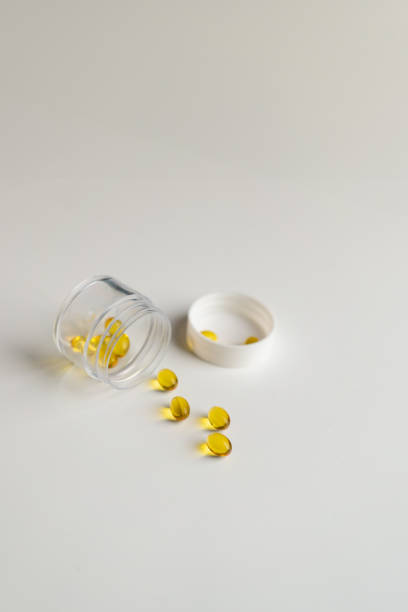istock Open bottle of yellow capsule vitamins on white background 2185663391