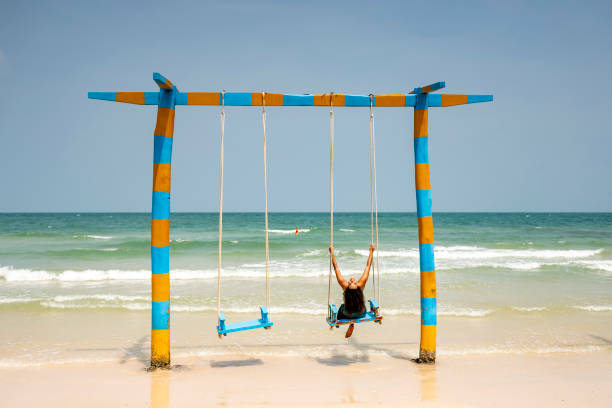 Happy little boy having fun while swinging on the beach. Copy space.
