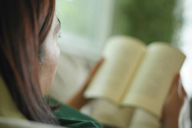 Woman lying down reading a book on the sofa