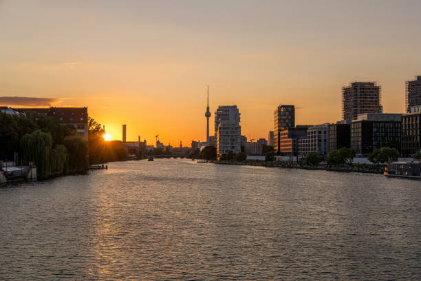 Stockholm, Sweden - May 22, 2022: Beautiful spring city sunset with two people sitting by waters edge with orange sky in Stockholm Sweden May 22, 2022.