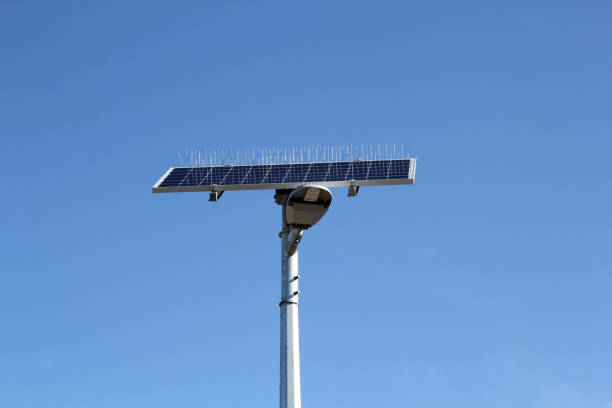 Solar-powered street light with bird spikes against a blue sky background