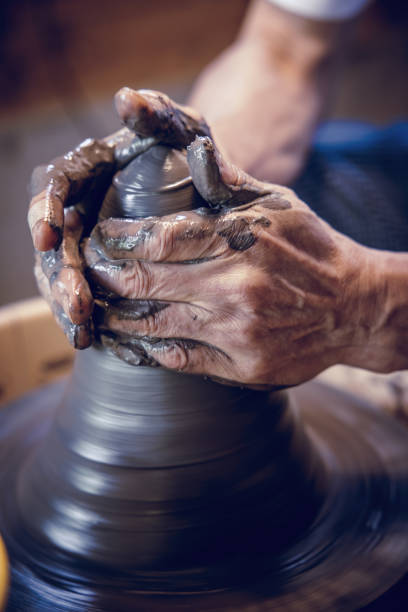 istock Hands of a potter shaping clay on a spinning wheel 2185676126