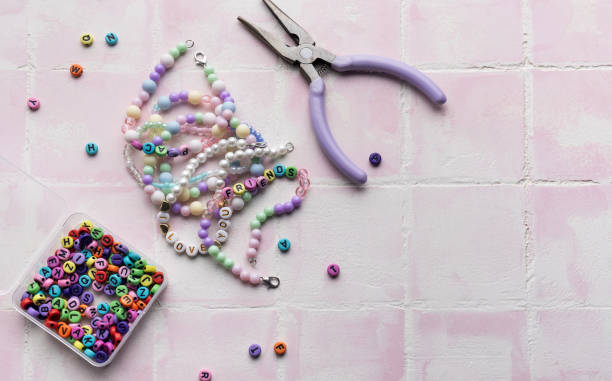 istock Colorful beads and jewelry making tools arranged on pink tile surface 2185677000