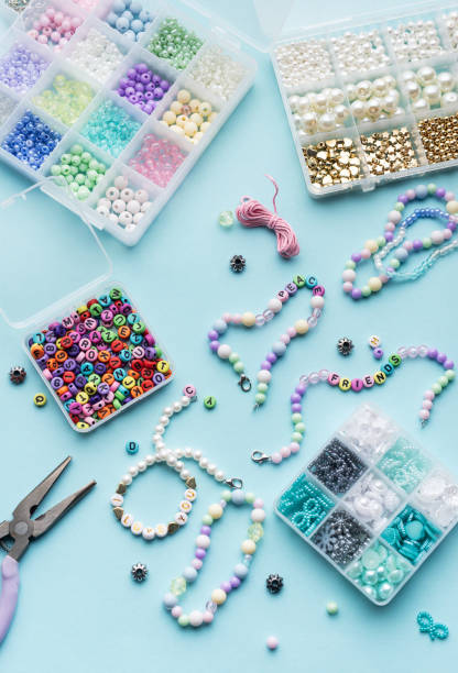 istock Colorful assortment of beads and jewelry-making tools on a blue surface with completed bracelets 2185677005