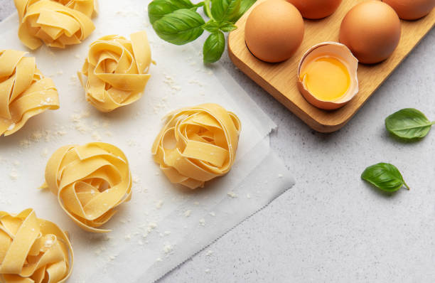 istock Fresh tagliatelle pasta nests with eggs and basil leaves on baking paper 2185677428
