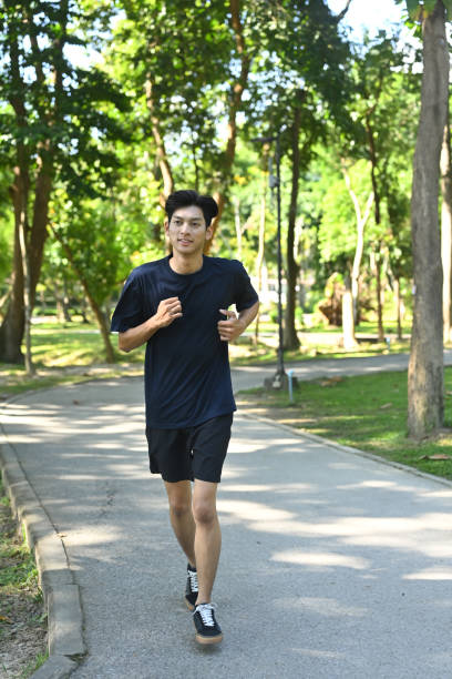istock Happy smiling man jogging through a park during the late afternoon 2185680176