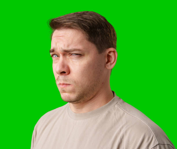 istock A man stands with arms crossed and a thoughtful expression in front of a green screen 2185680904