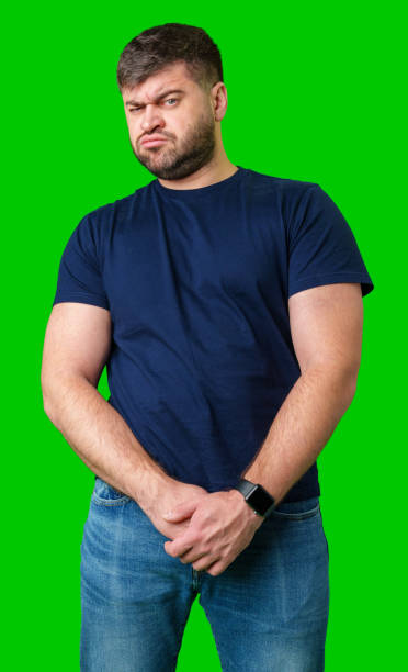 istock Man standing with a thoughtful expression in a casual outfit against a green background 2185682027